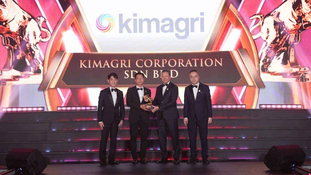 Kimagri representatives accepting the Golden Bull Award 2026 on stage, in front of a screen reading Kimagri Corporation Sdn Bhd.