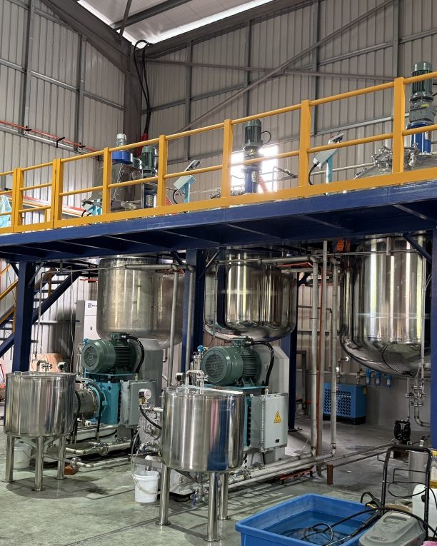 Kimagri's formulation plant: stainless steel mixing vessels beneath a yellow-railed access gantry inside the Kampung Kepayang facility.